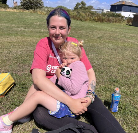 Georgia sat on the grass with her younger sister sat in her lap 