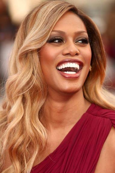 Laverne Cox smiling looking to the right wearing a one shoulder red dress. Black history month